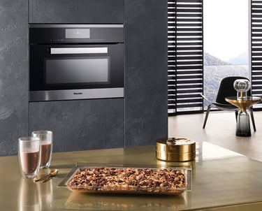 a kitchen with a large glass oven and a table with a glass of wine