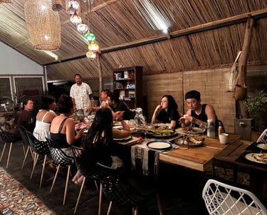 A group of friends enjoying a traditional dinner at a rustic bamboo restaurant with hanging lanterns.
