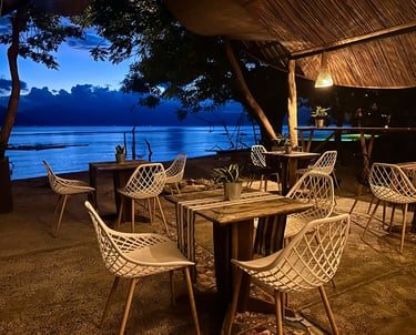 Cozy outdoor beachfront restaurant seating with white modern chairs at twilight.