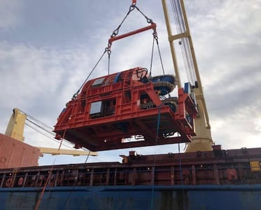Industrial equipment being lifted onto a cargo ship with crane