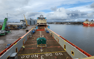 Panoramic view of a cargo ship docked at port with cranes and equipment on deck