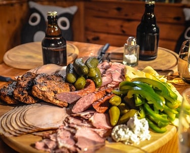 Una mesa de madera llena de comida y dos botellas de cerveza