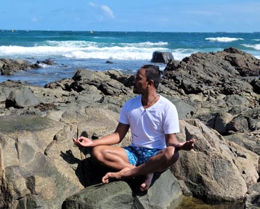 Wil in meditative pose near the ocean on rocks