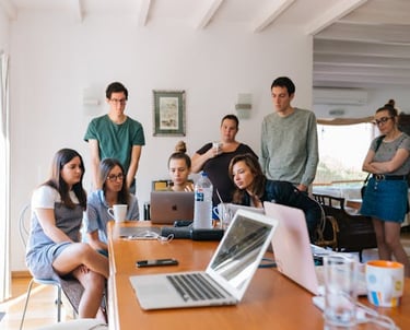 A team gathered around a laptop on a table, attending a virtual meeting.