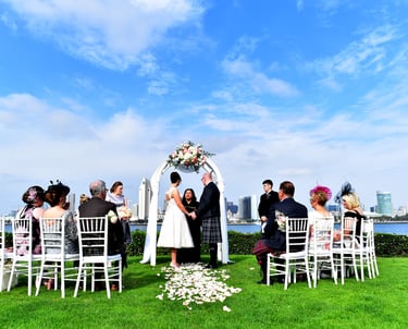 Bride and groom in Kilt, holding hands under wedding arch at Centennial Park, Coronado