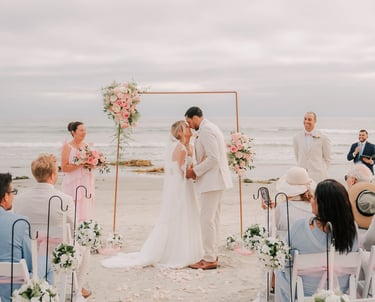 Bride & Groom kissing under arbor pink and white wedding at South Beach, Coronado