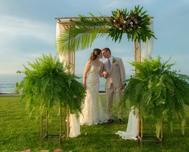 couple kissing under tropical wedding arbor at ellen browning scripps park, la jolla