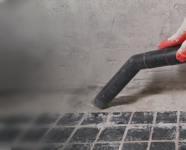 Mão a operar um aspirador durante a limpeza pós-obra, evidenciando a remoção de detritos