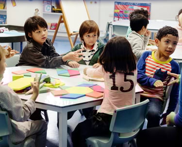 A teacher giving a group of students feedback as they work collaboratively on a task.