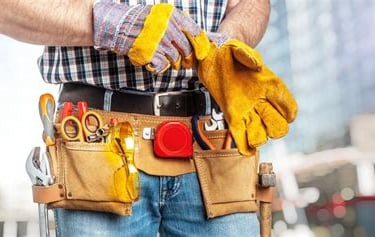 Handyman with tool belt putting on gloves ready to work