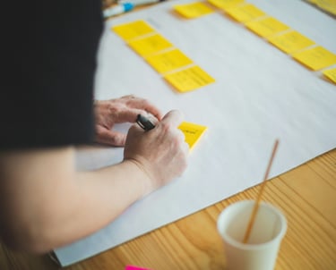 a person writing on sticky note with a pen