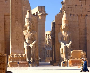 a woman in a blue dress standing in front of a large statue