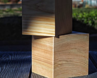 Two stacked cypress wood blocks showing natural grain texture on a rustic wooden table.