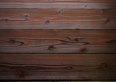 Close-up of dark stained cedar wood planks with visible natural grain and knots for rustic texture.