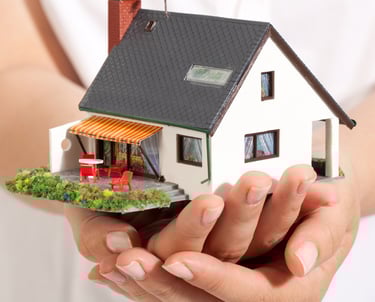 a person holding a miniature house in their hands