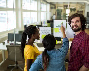 Um homem e uma mulher estão em pé em uma sala com um quadro branco na Martech Coders Academy