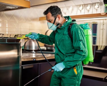 a man in a green uniform is spraying a kitchen counter