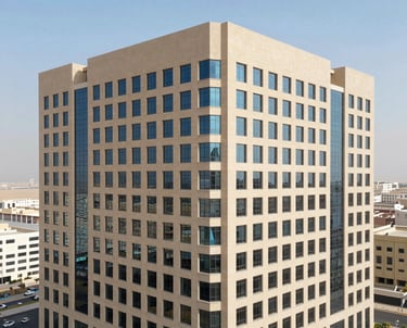 An aerial photograph of a newly completed office complex in Dammam, highlighting the sand-colored facade and modern glass windows under a clear bright sky. The composition showcases geometric precision and clean lines.