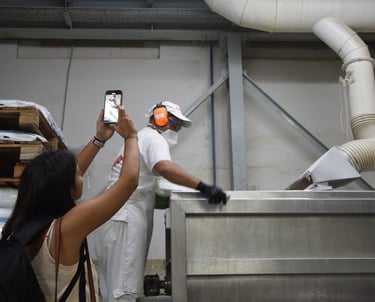 una joven filmando a un operario en una fábrica