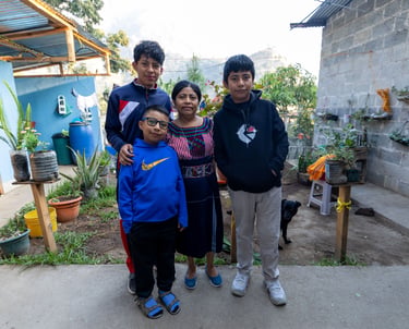 Guatemalan coffee-growing family standing together at their home in San Juan, Guatemala.