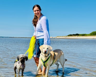 Svenja steht mit ihren Hunden Pelle und Paula im flachen Wasser der Nordsee.