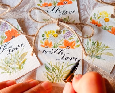 NYC calligrapher writing the words “with love” for a gift tag with handmade watercolor florals