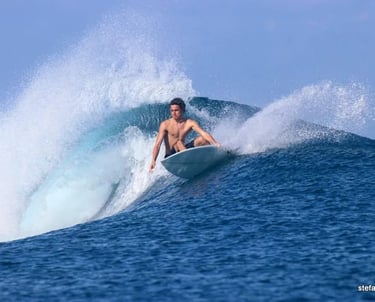 Surfer carving a sharp turn on a turquoise wave at a secret Mentawai spot
