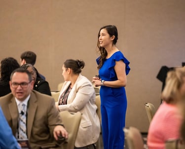 Woman in blue jumpsuit leading an Unleashing Radiance empowerment event for professional women.