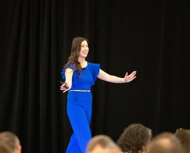 Ellen welcoming audience on stage in blue jumpsuit