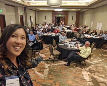 Smiling woman hosting Unleashing Radiance workshop with large audience