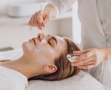 Vrouw dat met een fijn borsteltje een gezichtmasker krijgt toegediend 