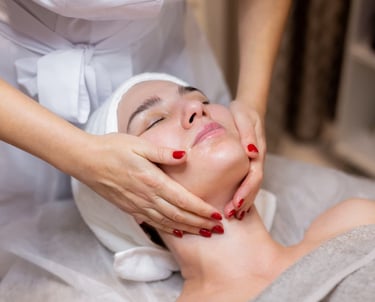 een vrouw met rode nagels dat een andere vrouw haar gezicht vast heeft om te masseren