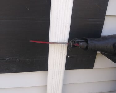 Using a saw to cut a downspout to install a rain barrel under it to collect rainwater 