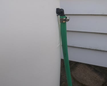 a hose clamped onto a rain barrel overflow