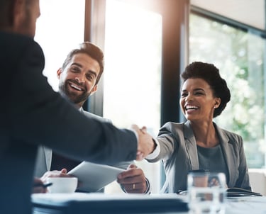Smiling professionals shaking hands in a business meeting, symbolizing successful career transitions