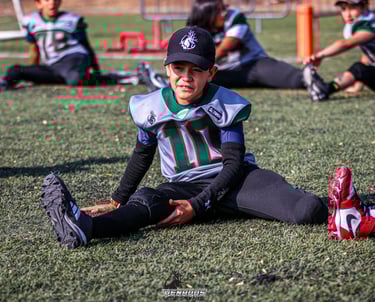 Joven miembro del equipo de football americano estirando