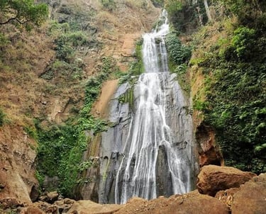 Hikers approaching Mataru Waterfall through lush forest in alor