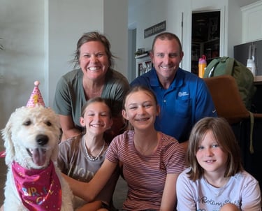 Family smiling at their new home with dog