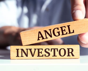 a person holding a wooden block with the words angel investor