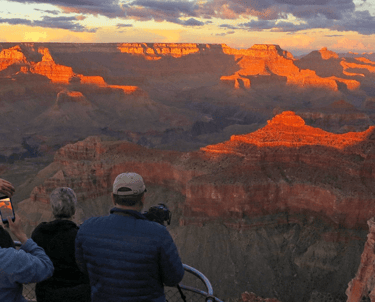 a group of people standing on a cliff overlooking a canyon