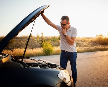 a man standing in front of a car with a broken hood