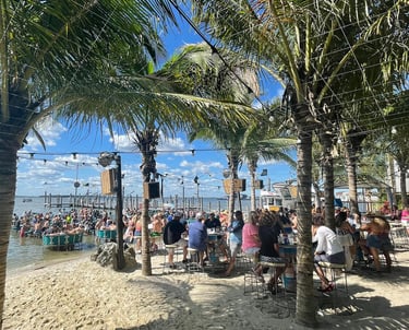 a beach with people sitting at tables and palm trees