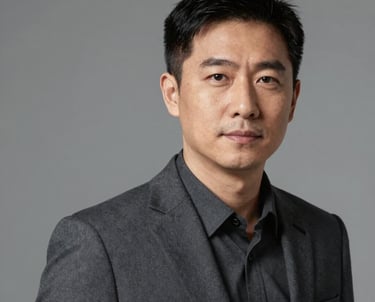 Professional headshot of a male technical consultant in a dark slate gray suit, neutral background, looking professional and approachable.