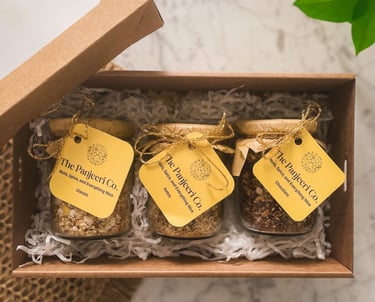 A gift box containing three glass jars of Panjeeri flavours: chocolate, dates, and classic