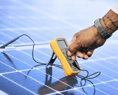 A technician uses a digital multimeter to test and maintain solar panels for efficient energy output.