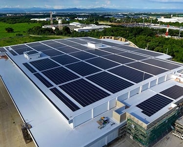 Aerial view of a large commercial building roof installed with a massive solar panel system.