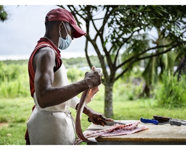 Un homme découpe un poisson au marché en Guyane