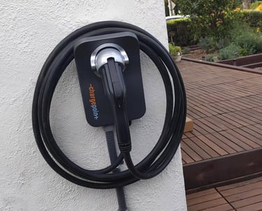 ChargePoint home electric vehicle charging station mounted on a white wall next to a wooden deck.