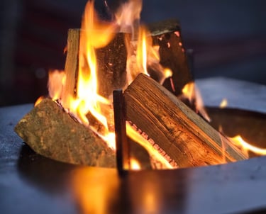 A warm outdoor fire pit with burning wood logs and glowing orange flames.