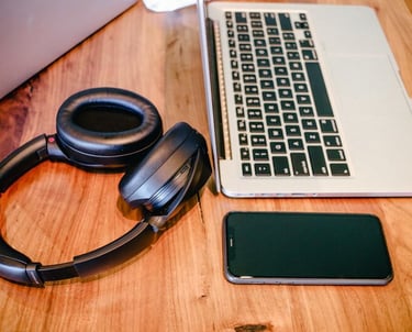 a laptop, a mobile phone and some headphones on a table